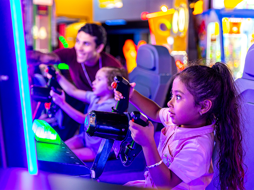 a young girl playing arcade games with her dad